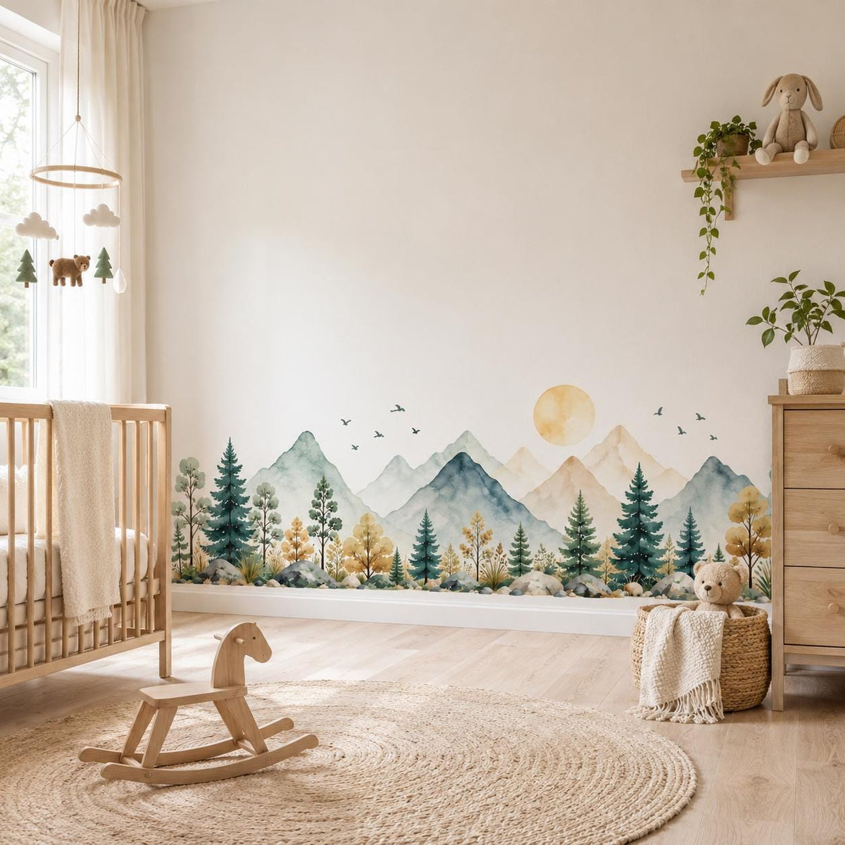 Panoramic mountain and pine tree wall decal behind a wooden crib and rocking horse in a nursery.
