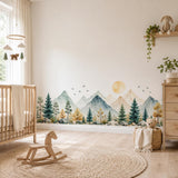 Panoramic mountain and pine tree wall decal behind a wooden crib and rocking horse in a nursery.