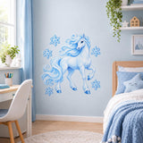 Blue unicorn and snowflakes vinyl wall sticker between a white desk and a bed in a winter-themed room.