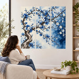Woman seated in an armchair looking toward a blue flowering tree wall decal in three panels.