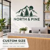 Custom-sized green North & Pine logo wall decal with mountain and pine tree artwork above a modern reception counter.