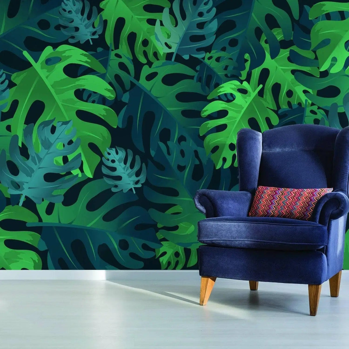Tropical paradise wallpaper featuring lush green leaves, complemented by a stylish blue armchair with a colorful pillow.