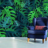 Tropical paradise wallpaper featuring lush green leaves, complemented by a stylish blue armchair with a colorful pillow.