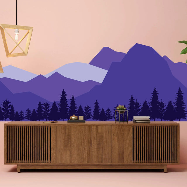 Majestic mountain wall decal in purple tones enhancing a stylish living room with wooden furniture and warm lighting.