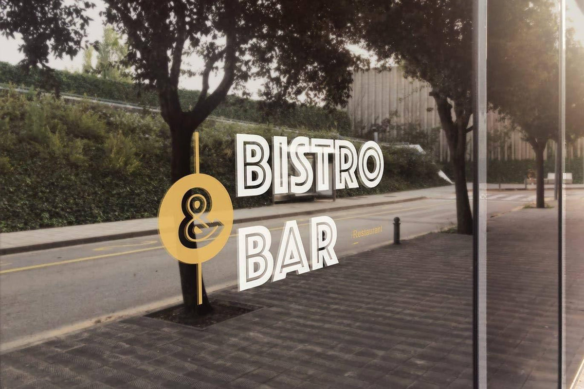 Bistro and Bar sign displayed on a window with reflection of trees and street in the background.