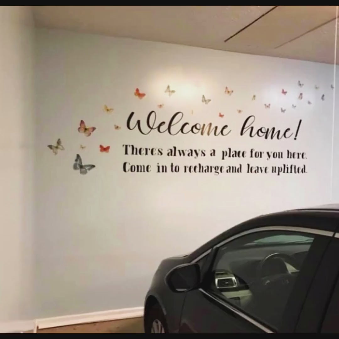 Vinyl lettering wall decal with butterflies saying 'Welcome home! There's always a place for you here' in a garage.