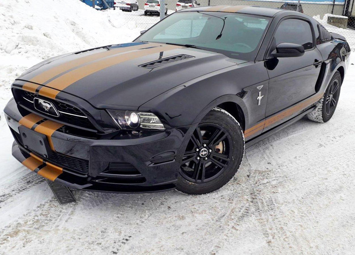 Black car with racing stripes in snow, showcasing stylish vinyl decals for a sporty appearance.