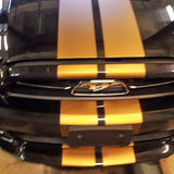 Black car with yellow racing stripes on the hood, showcasing sporty vinyl decals for a stylish upgrade.