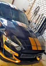 Sleek black car with orange racing stripes vinyl decals in garage, showcasing sporty vehicle graphics.