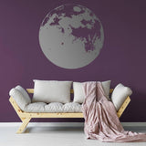 Vinyl wall sticker of a large moon on a purple wall, enhancing a cozy living space with modern decor.