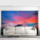 Stunning sunset wall mural above a modern white couch in a stylish home interior.