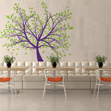 Tree wall decal in purple and green decorates a modern café with white seating and orange accents.