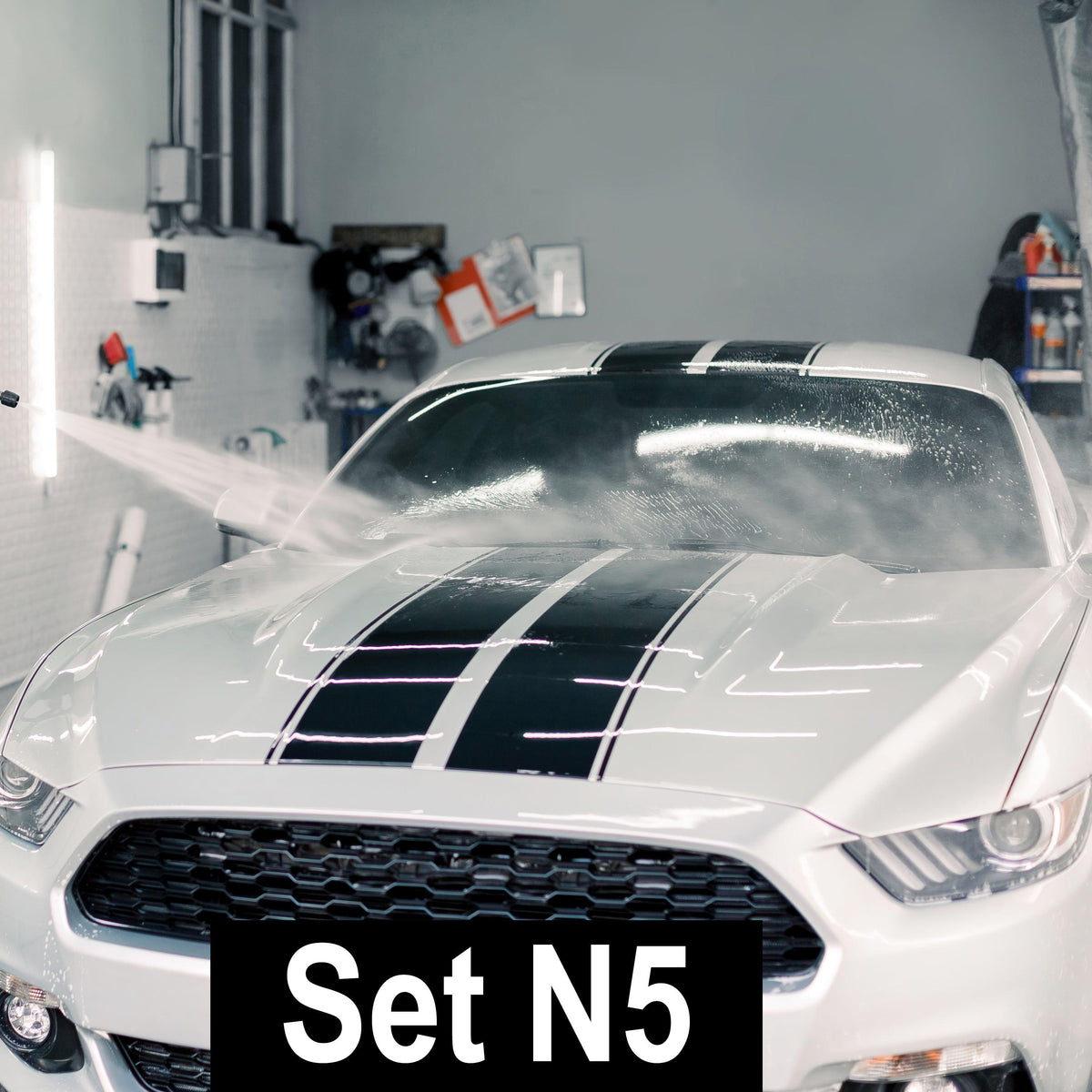 Stylish black racing stripes on a white car being cleaned, showcasing vibrant vinyl car decals in a workshop setting.