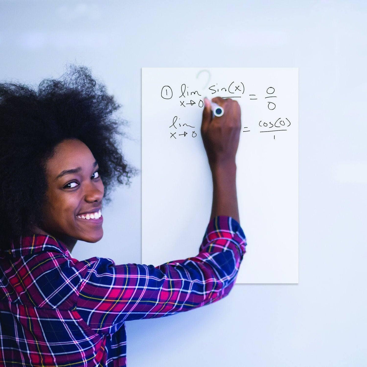 Woman using a dry erase sticker to solve math problems on a smooth surface with a marker.