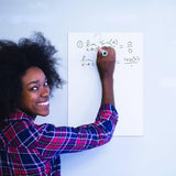 Woman using a dry erase sticker to solve math problems on a smooth surface with a marker.