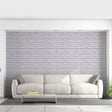 Modern living room with a peel and stick brick wallpaper accent wall behind a white sofa.