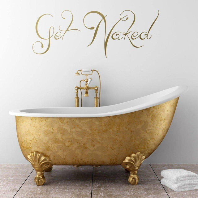 Elegant golden bathtub with 'Get Naked' wall decal, adding humor to bathroom decor.