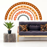 Boho chic rainbow wall decal above modern sofa with colorful pillows and a potted plant, adding charm to the living space.