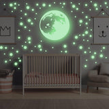 Glow in the dark moon and star wall stickers illuminating a nursery, creating a magical celestial theme.