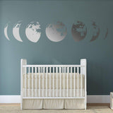 Moon phase wall sticker decor above a white crib in a nursery with a calming dark blue wall.