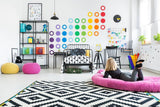 Colorful circle wall decals in a vibrant kids' room with a girl lounging on a pink cushion.