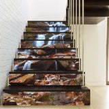Rocky waterfall stair riser decals on a modern staircase, forming a continuous stream and stone mural across the steps.