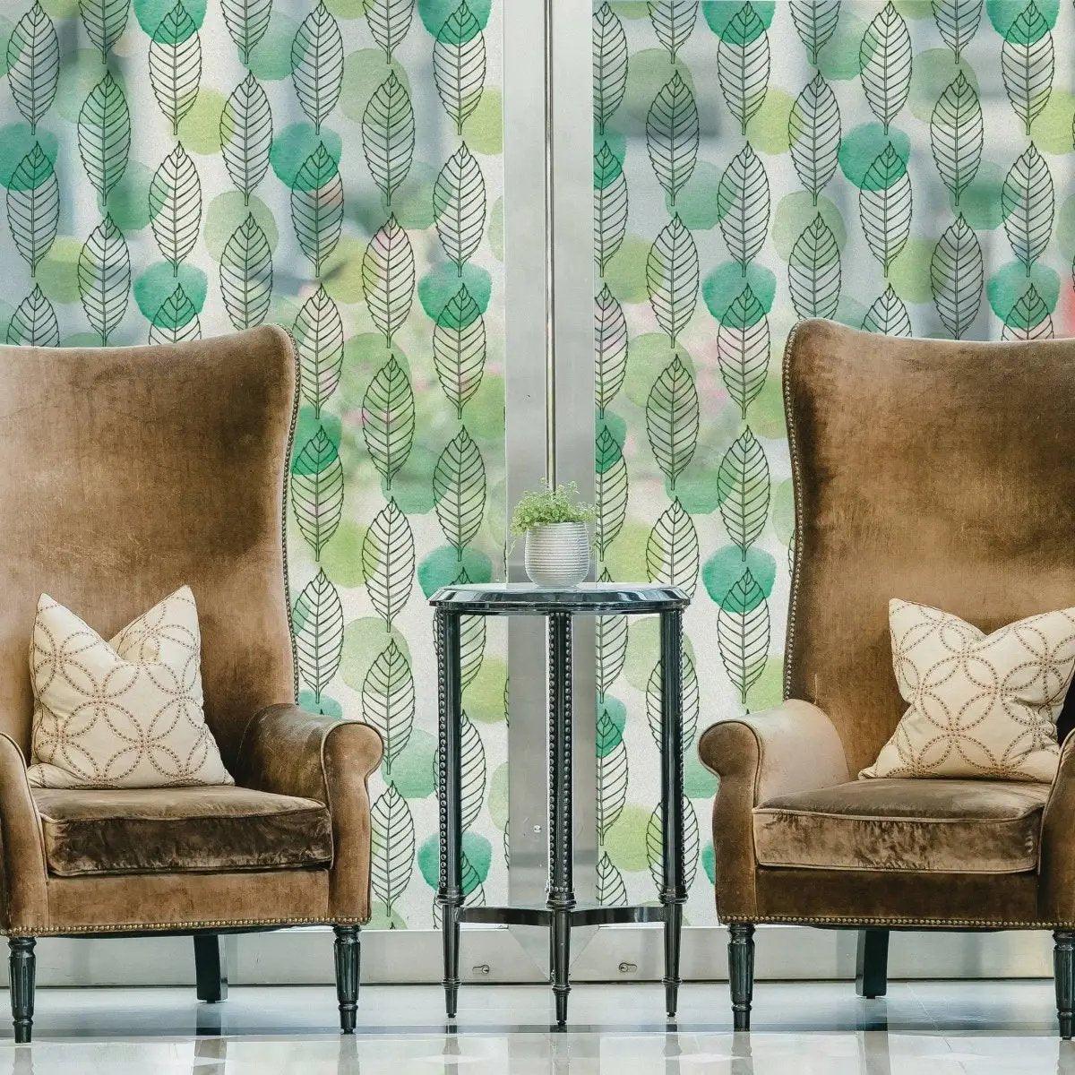 Stylish leaf design window film enhancing privacy in a cozy living room with elegant armchairs and decor.
