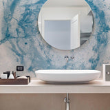 Elegant bathroom featuring blue marble effect wallpaper and a round mirror above a modern sink.