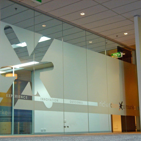 Frosted glass window film featuring geometric designs and company branding in an office space.