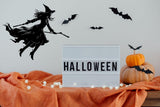 Flying broom figure silhouette vinyl decal displayed in a room setting.