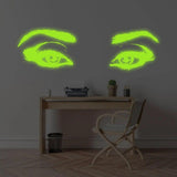 Glowing luminescent vinyl wall decal of eyes above a wooden desk, illuminating the room with enchanting light.