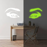 Glowing luminescent eye vinyl wall decal illuminating a workspace at night, captivating glow effect.