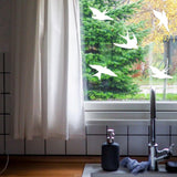 Bird safety window decals by FeatherGuard displayed on a sunny kitchen window.