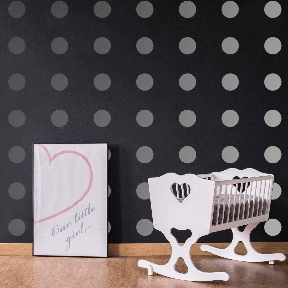 Stylish nursery featuring gray circle wall decals, a white rocking crib, and framed art on a black wall.