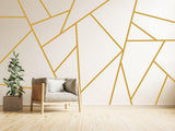 Elegant gold geometric wall stickers design with modern decor, featuring a cozy chair and potted plant.