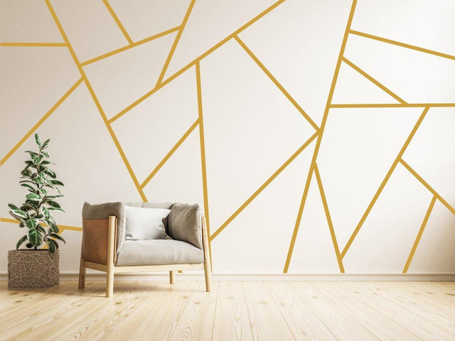 Elegant gold geometric wall stickers design with modern decor, featuring a cozy chair and potted plant.