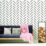 Herringbone wall stickers in black on white background with a cozy couch and decorative blanket in a stylish living room.