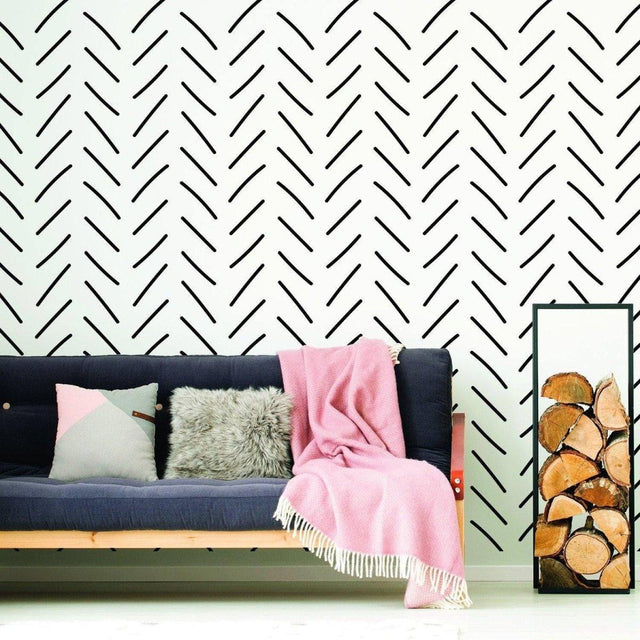 Herringbone wall stickers in black on white background with a cozy couch and decorative blanket in a stylish living room.