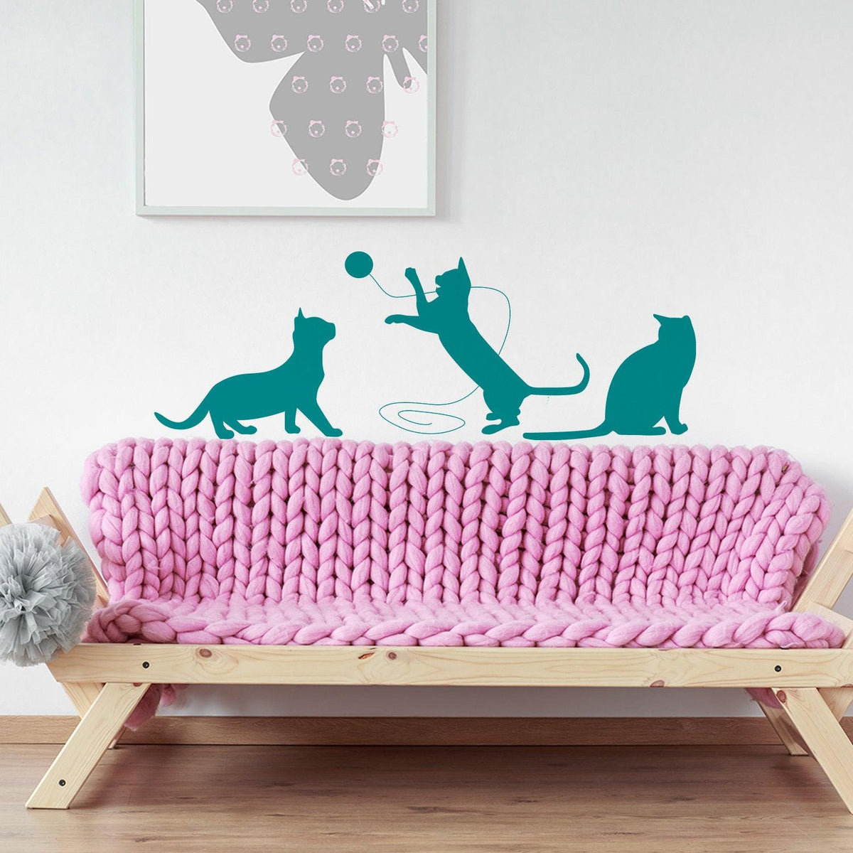 Colorful cat wall decals above a cozy pink knitted sofa in a stylish interior setting.
