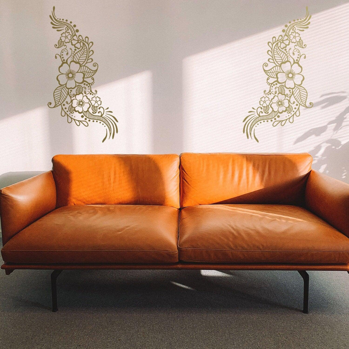 Henna tattoo wall vinyl stickers in floral mandala design above a brown leather sofa.