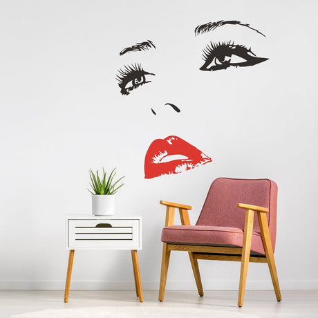 Elegant woman face vinyl wall decal in black and red above a pink chair, adding beauty and style to home decor.
