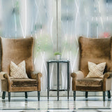 Stylish sitting area with brown armchairs and a side table, featuring frosted glass window for privacy.