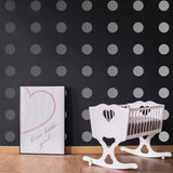 Stylish nursery featuring gray circle wall decals, a white rocking crib, and framed decor for a chic look.