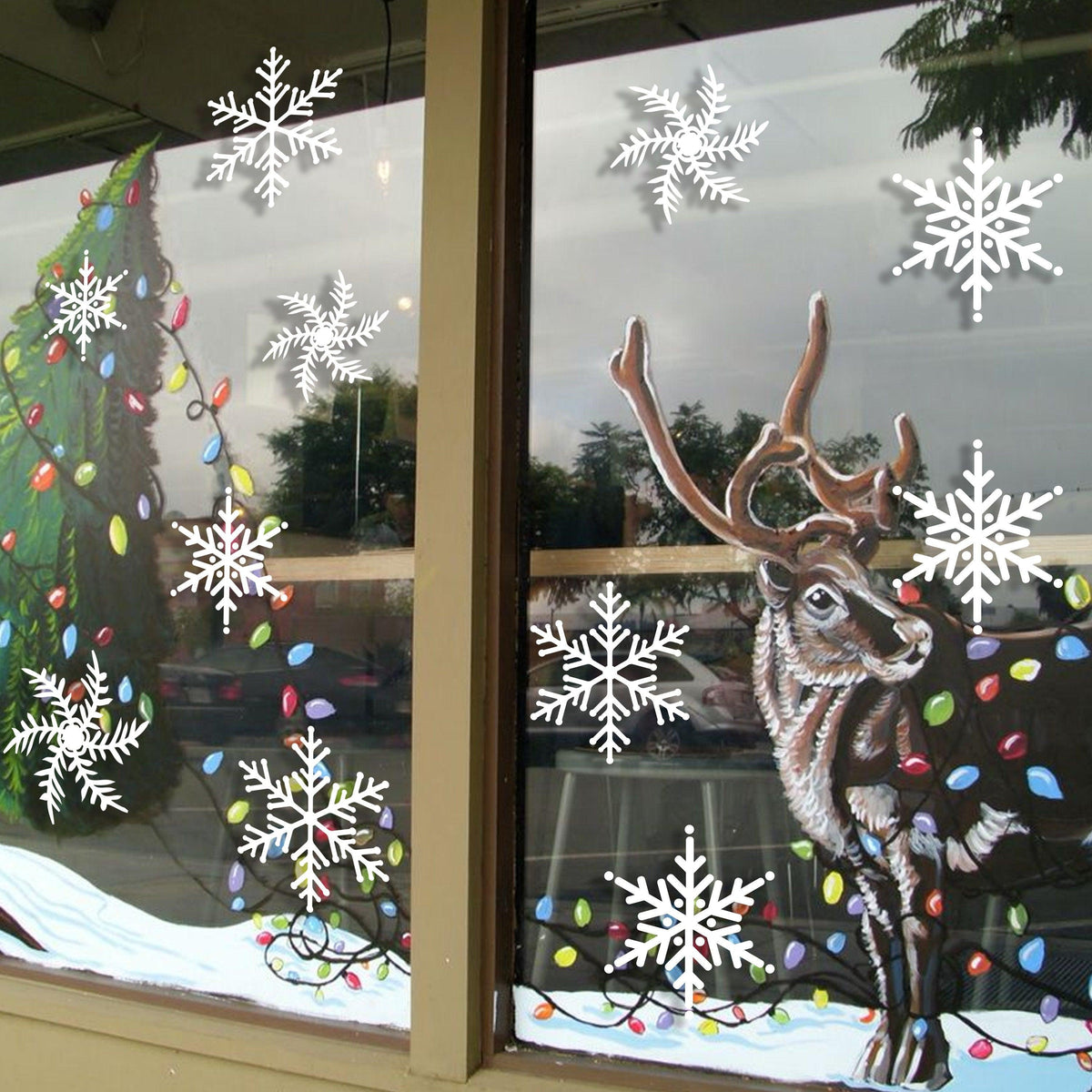 Christmas window decor featuring snowflake stickers and a reindeer with festive lights.