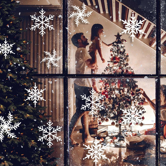 Family decorating a Christmas tree with snowflake window stickers visible on the glass for a festive holiday atmosphere.