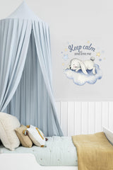 Baby nursery decor with a cozy cloud design, featuring a sleeping animal and a calming message above a bed.