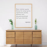Custom quote poster print displayed above a wooden sideboard with greenery, showcasing personalized text options.
