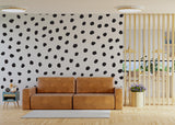Living room featuring a modern wall with irregular black polka dots and a cozy brown couch.