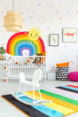 Colorful nursery with rainbow wall sticker, cheerful sun decal, and playful decor for baby's room.