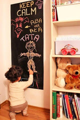 Child drawing on a chalkboard wall sticker, promoting creativity in a cozy home environment.